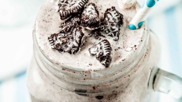 Close up of Blizzard Oreo Dessert in a clear mug with handle with two white and green straws coming out of the drink.