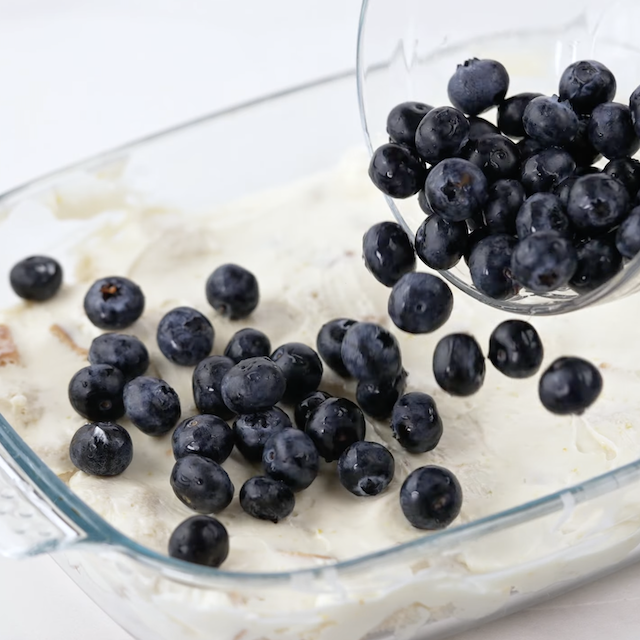 Blueberries being added to a casserole to make blueberry french toast casserole.