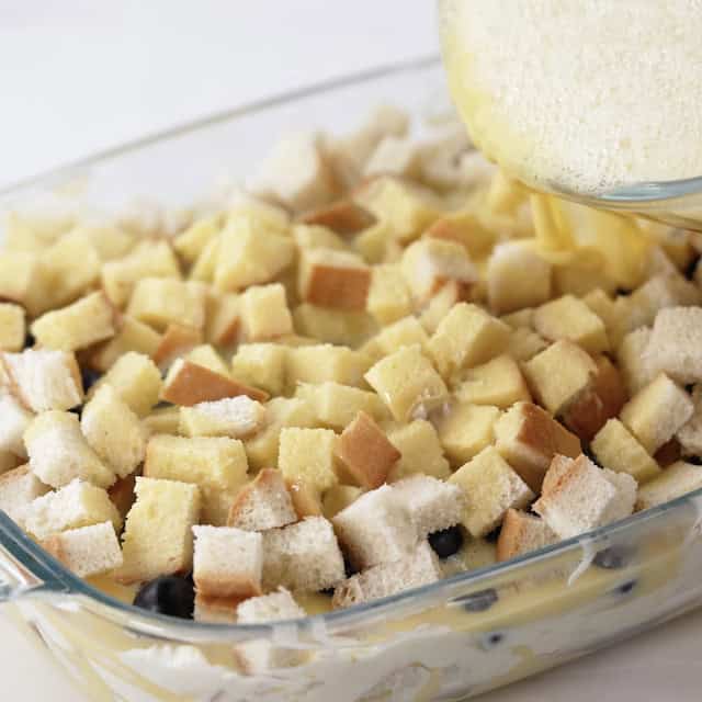 French toast mix being poured in a baking dish to make blueberry french toast casserole.