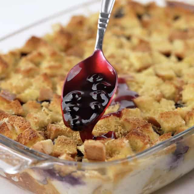 Homemade blueberry sauce being poured over freshly baked french toast casserole