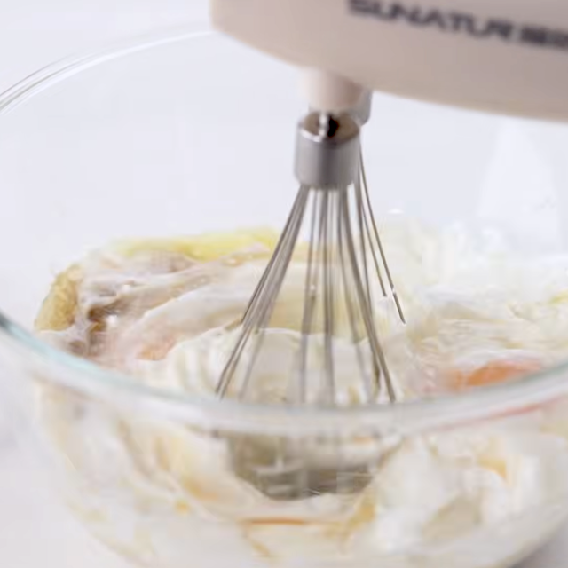 Wet ingredients to make fluffy buttermilk pancakes being mixed with a hand mixer