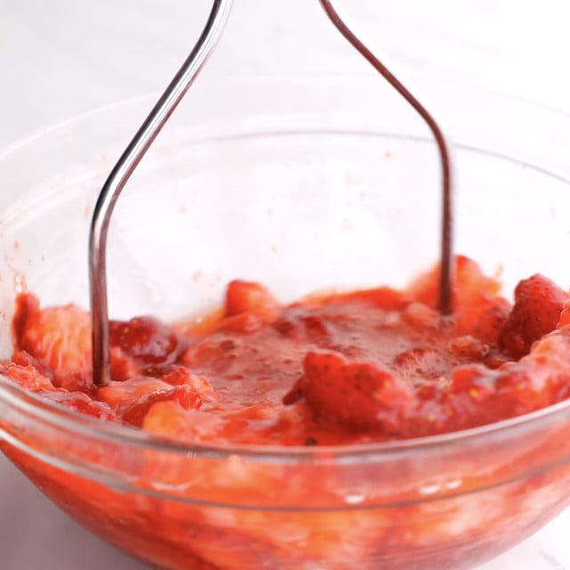 Strawberries being mashed to make strawberry pie at home.
