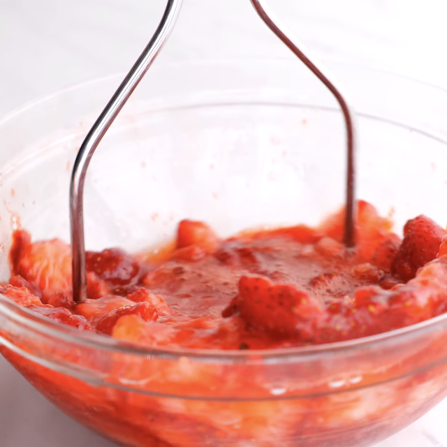 Strawberries being mashed to make strawberry pie at home.