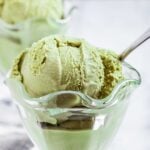 Scoops of homemade green tea ice cream in glass serving bowls with spoons.
