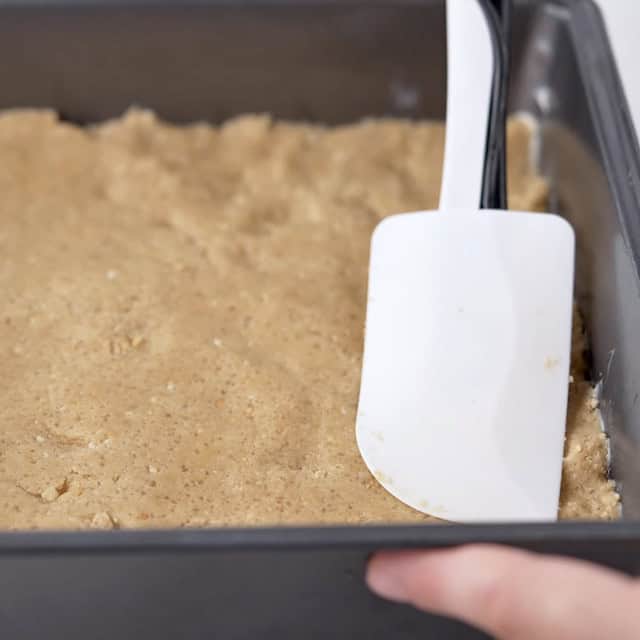 Smores bars base being pressed into a baking tray.
