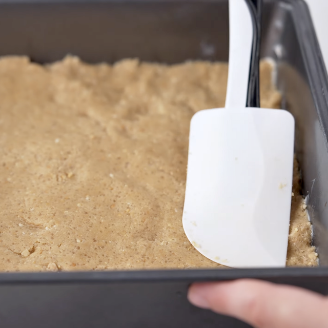 Smores bars base being pressed into a baking tray.