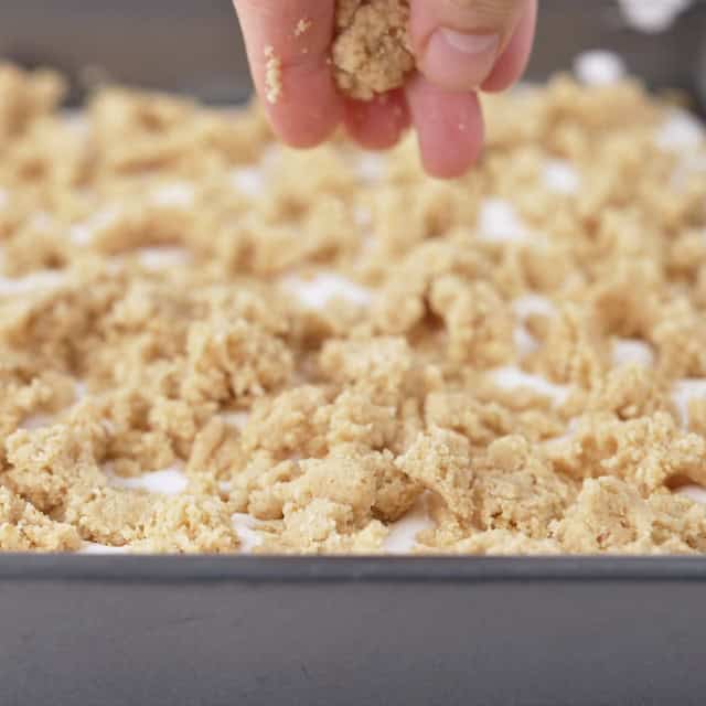 Crumble being sprinkled on top to make smores bars recipe.