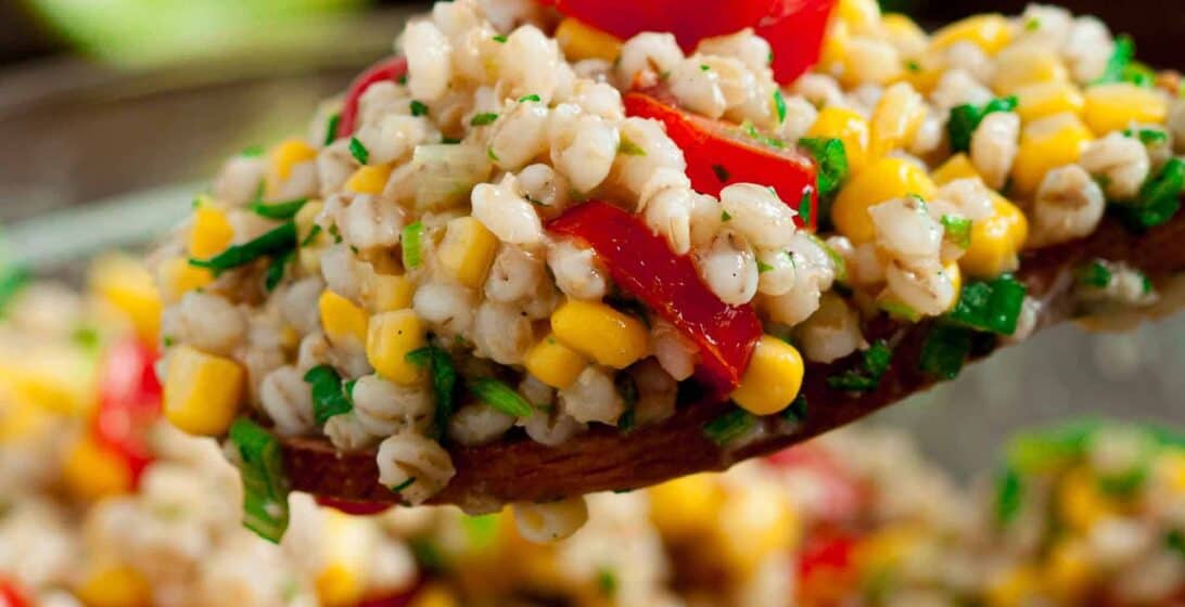 Close up spoonful of Barley Salad with fresh tomatoes and corn kernels.