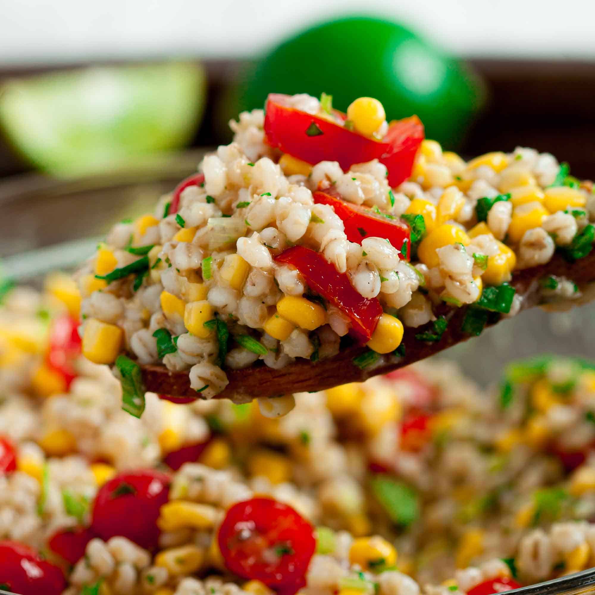 Close up spoonful of Barley Salad with fresh tomatoes and corn kernels.