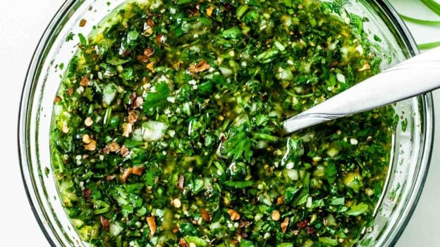 Mixing together all the ingredients in a clear glass bowl with a spoon, ready to serve or store until later.