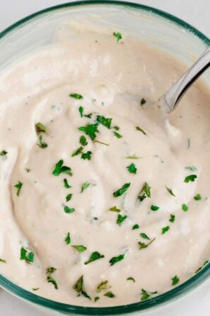 Creamy ceasar salad dressing in a clear bowl with a spoon.