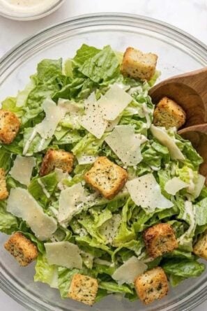 Bowl of Caesar salad with homemade dressing and croutons on top.