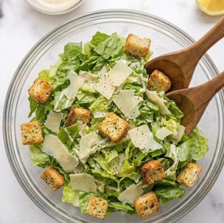 Bowl of Caesar salad with homemade dressing and croutons on top.