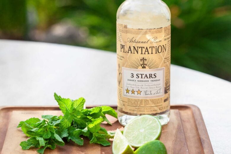Ingredients on a cutting board that are needed to make mojitos at home.