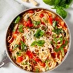 Close up of One Pot Tomato Basil Pasta in a serving bowl, topped with spinach leaves.