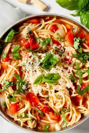 Close up of One Pot Tomato Basil Pasta in a serving bowl, topped with spinach leaves.
