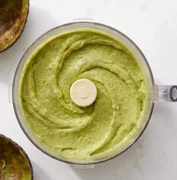 Blending the ingredients for the hummus with avocado until it's smooth and creamy.