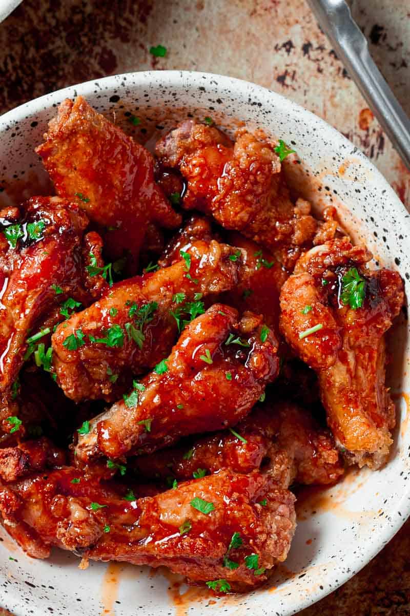 Close up of a plate of buffalo chicken wings on a white platter.