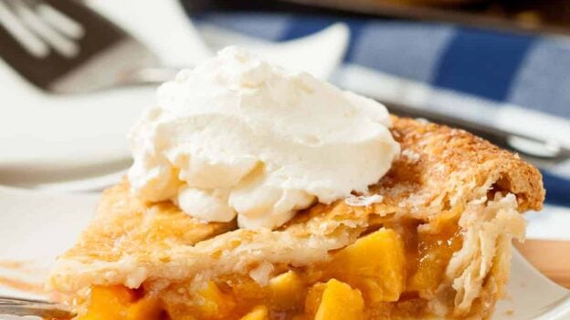 Peach pie slice with ice cream on top.