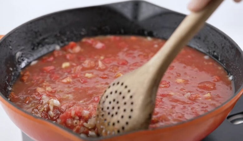 Stirring the sauce in the skillet with a brown spoon.