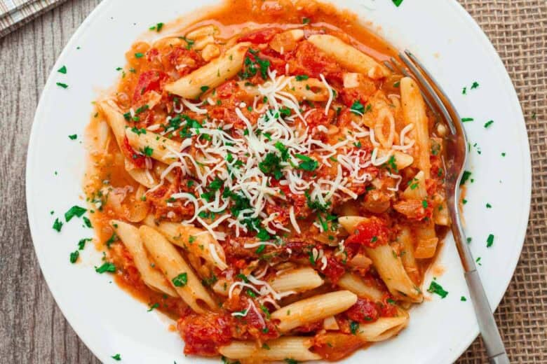 Plate of sun dried tomato pasta topped with grated Parmesan cheese.