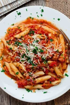 Overhead view of a white bowl full of sun dried tomato pasta.
