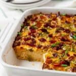 Bacon and Egg Casserole in a white Casserole dish with a piece removed.