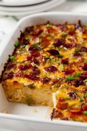 Bacon and Egg Casserole in a white Casserole dish with a piece removed.