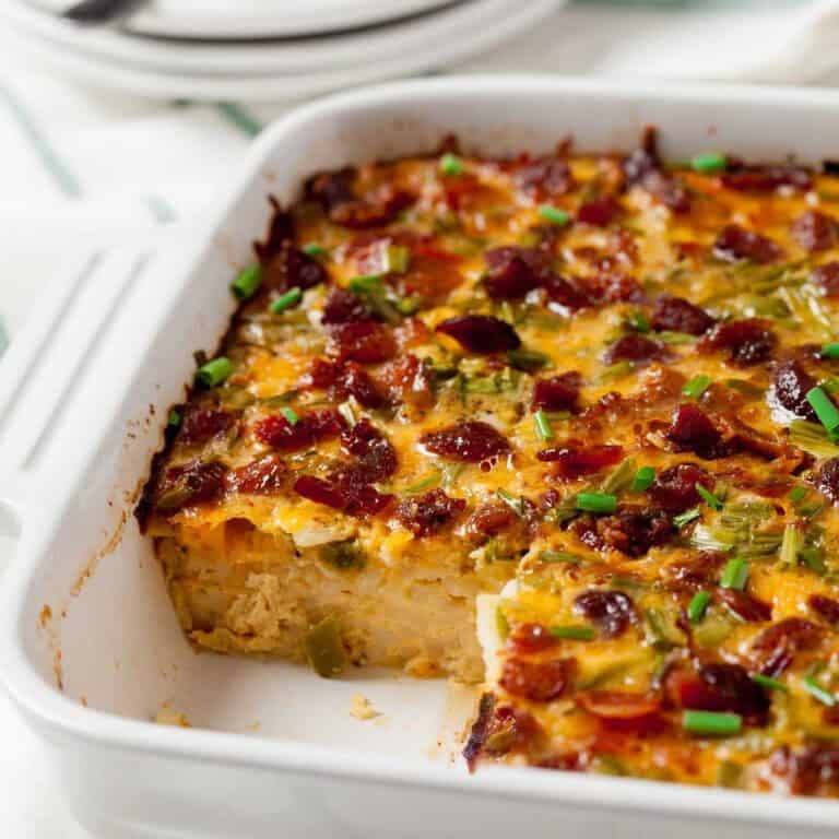 Bacon and Egg Casserole in a white Casserole dish with a piece removed.