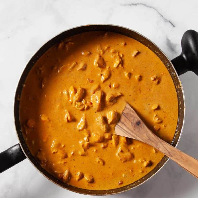 Mixing together the sauce ingredients with the chicken to thicken.