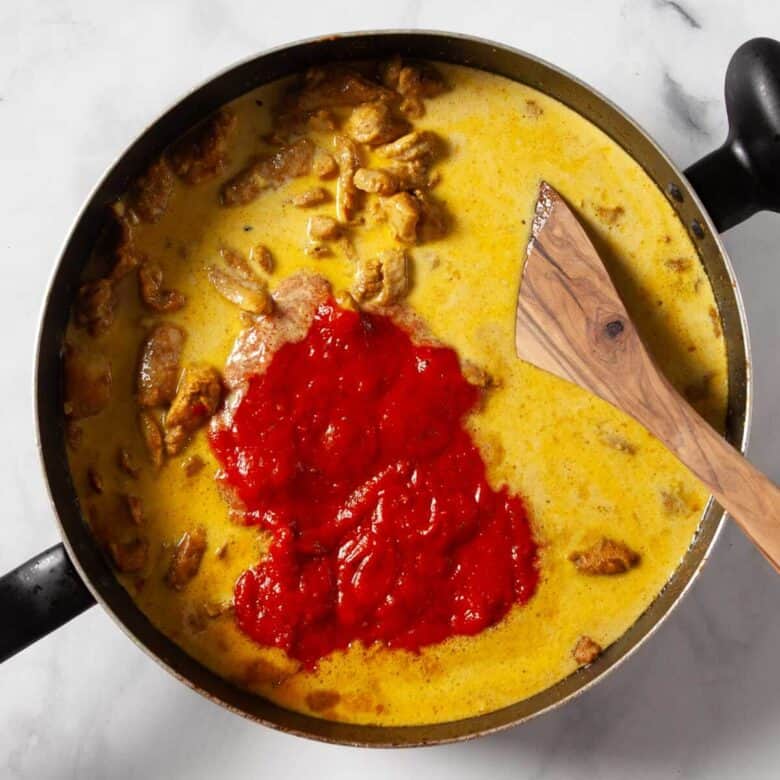 Adding the coated chicken into the sauce pan on the stove.