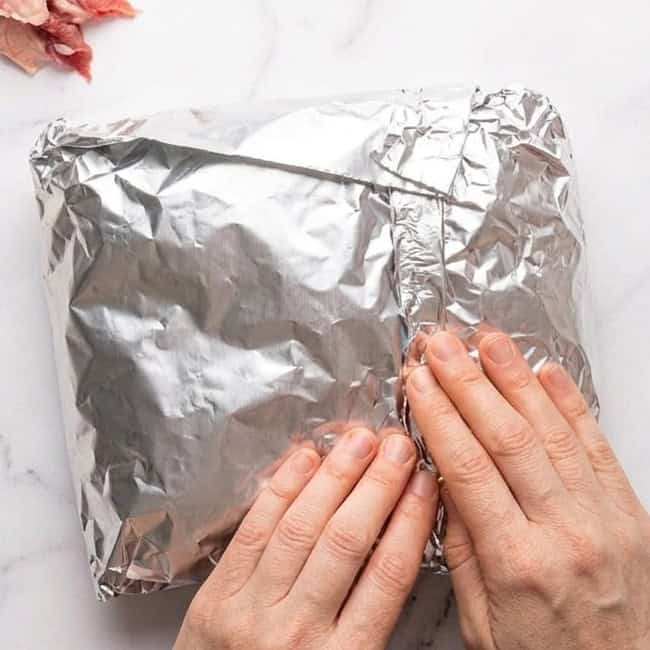 Wrapping the brisket in a large sheet of aluminum foil.