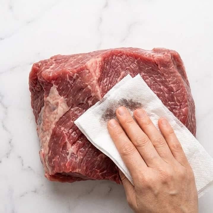 Patting the brisket dry using a clean paper towel.