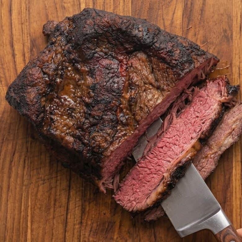 Placing the brisket on a wooden cutting board and cutting against the grain.