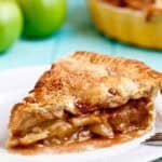 Apple pie with flaky butter crust sliced on a white plate.