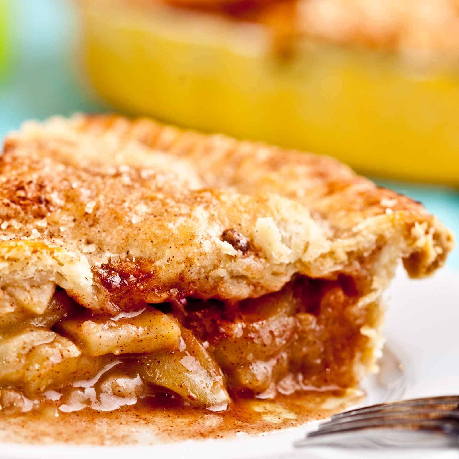 Apple pie with flaky butter crust sliced and close up shot on a white plate. 