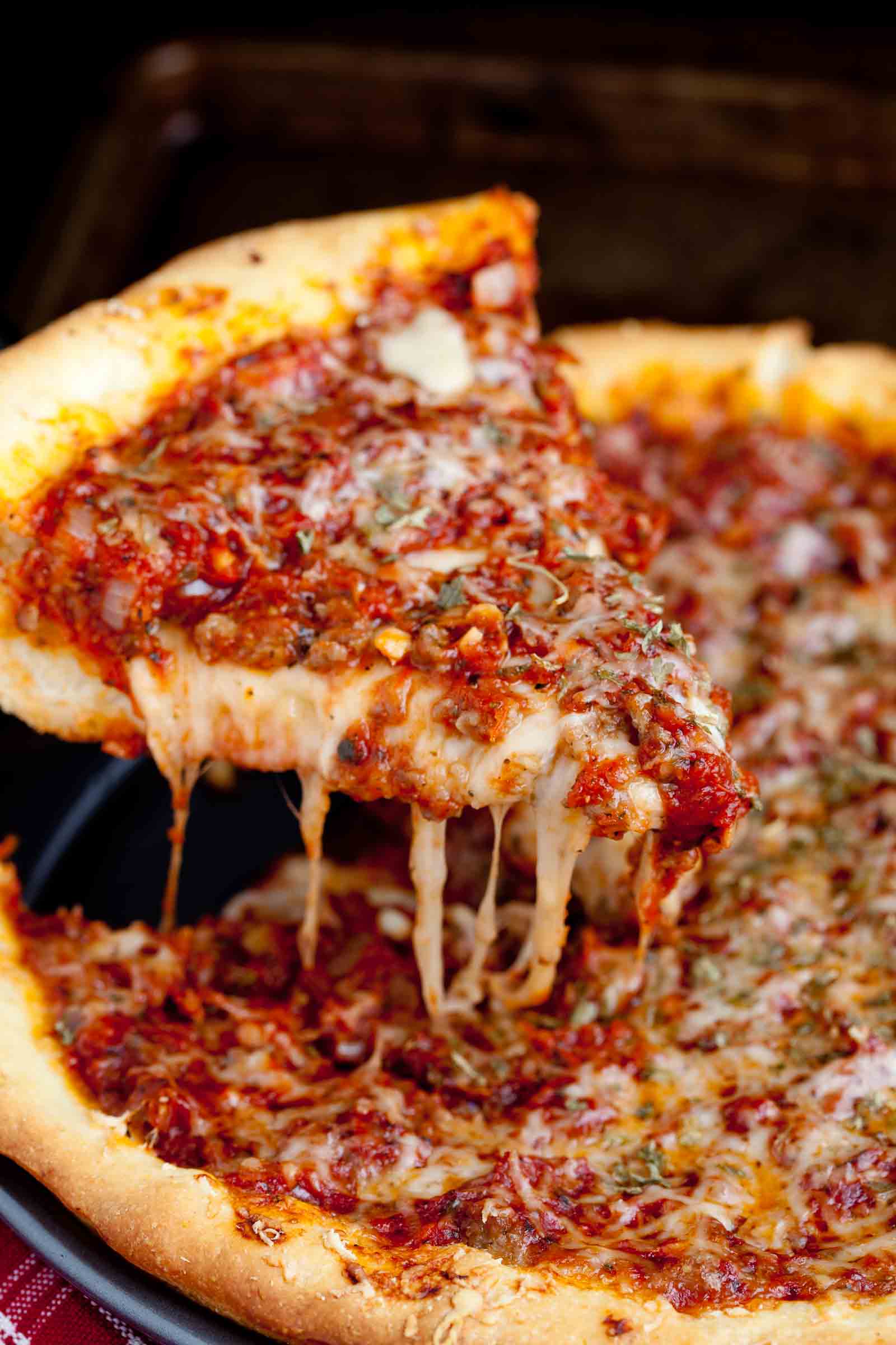 Spatula pulling out a piece of sliced deep dish pizza.