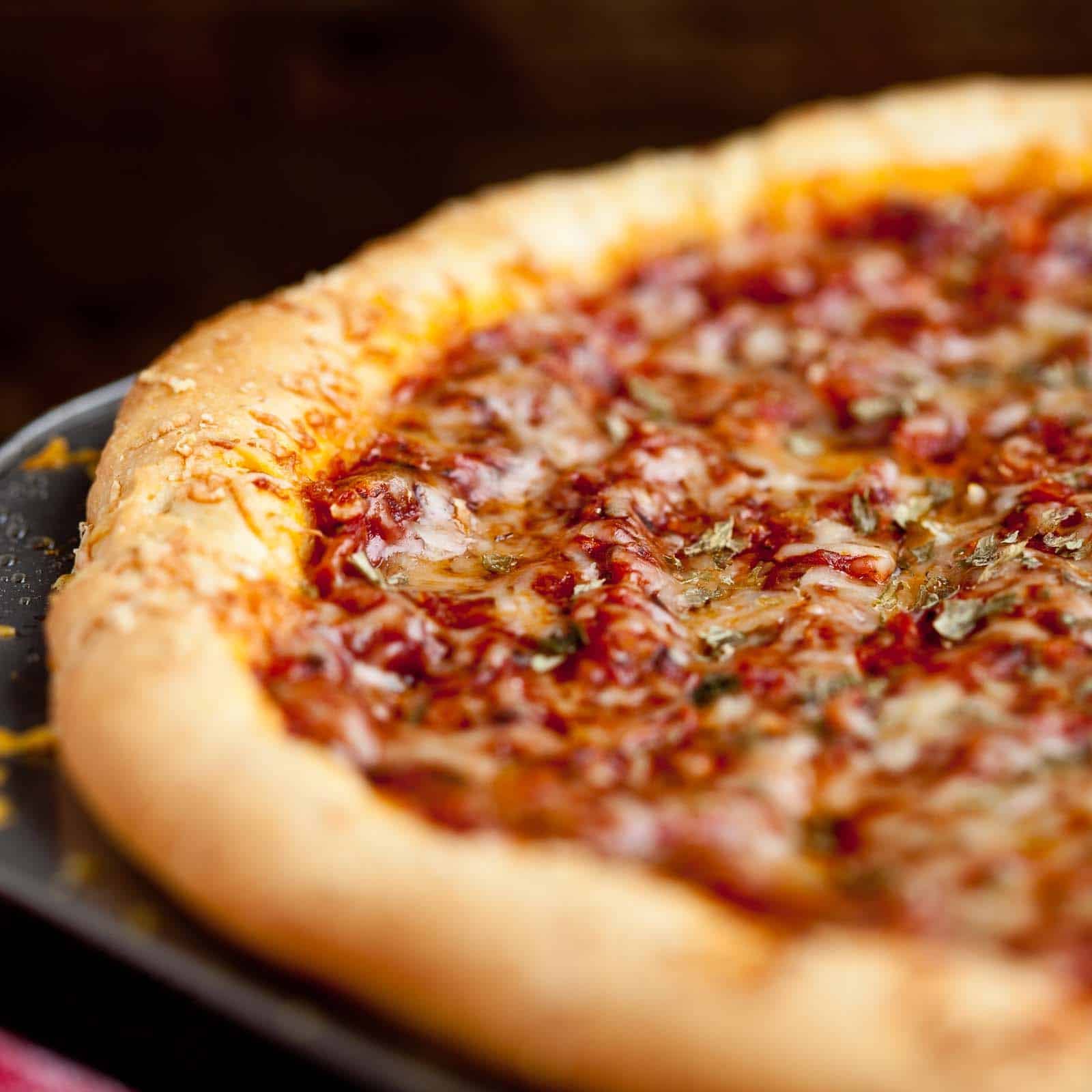 Showing the golden edges of the deep dish pizza baked in the pan.