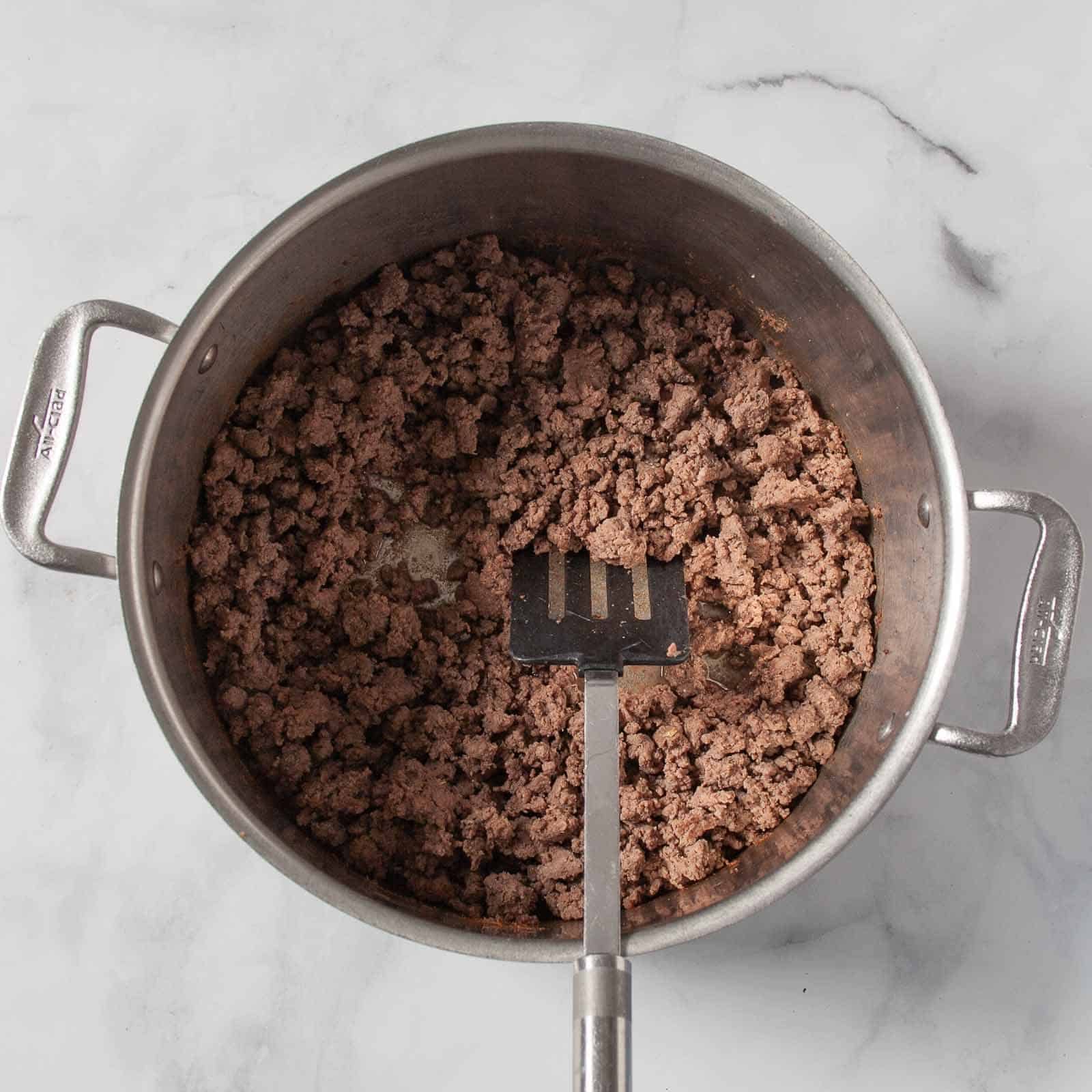 Ground beef cooking in a large pot for classic chili.