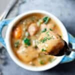 A person taking a spoonful of Instant Pot Chicken and Dumplings out of a white bowl.