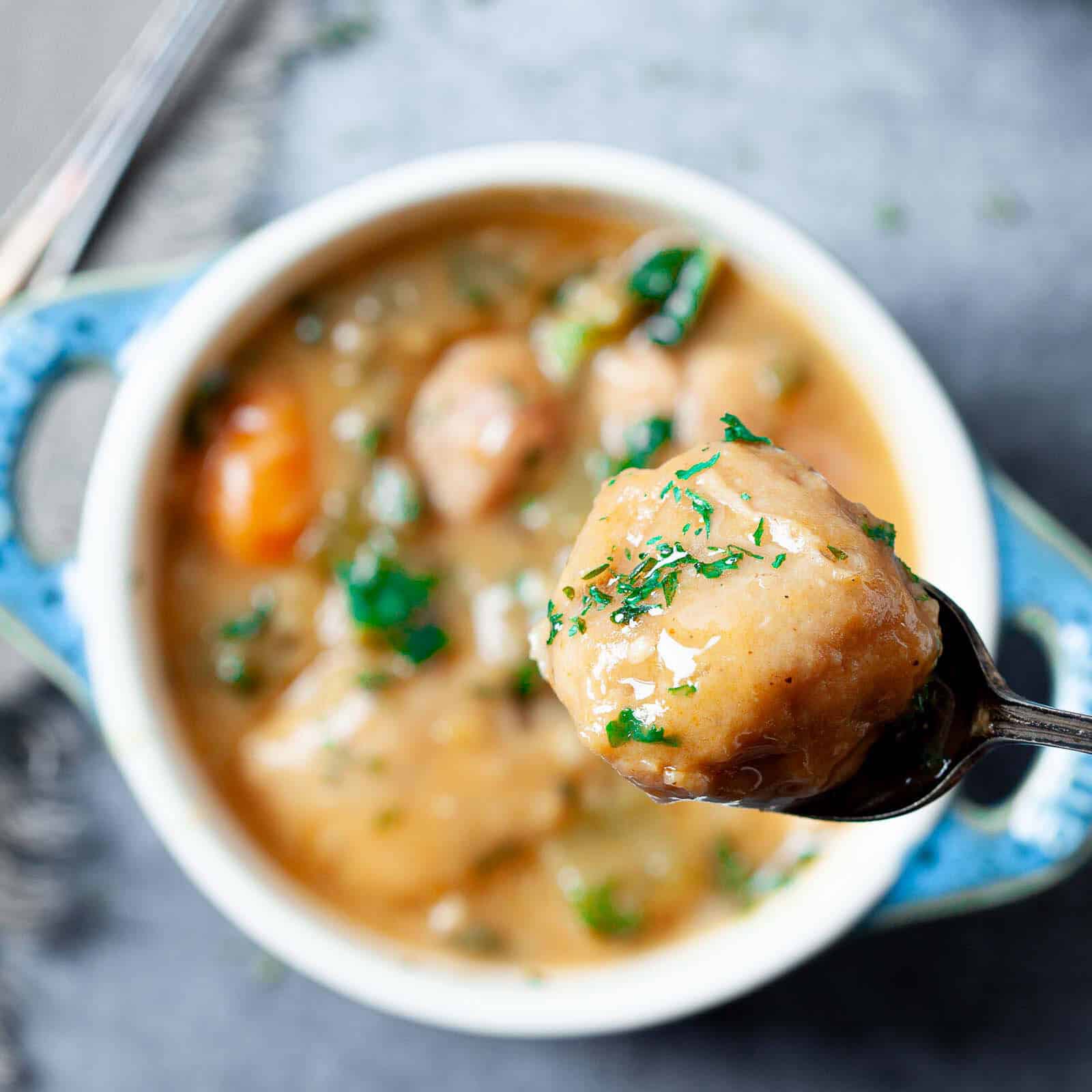 A person taking a spoonful of Instant Pot Chicken and Dumplings out of a white bowl.