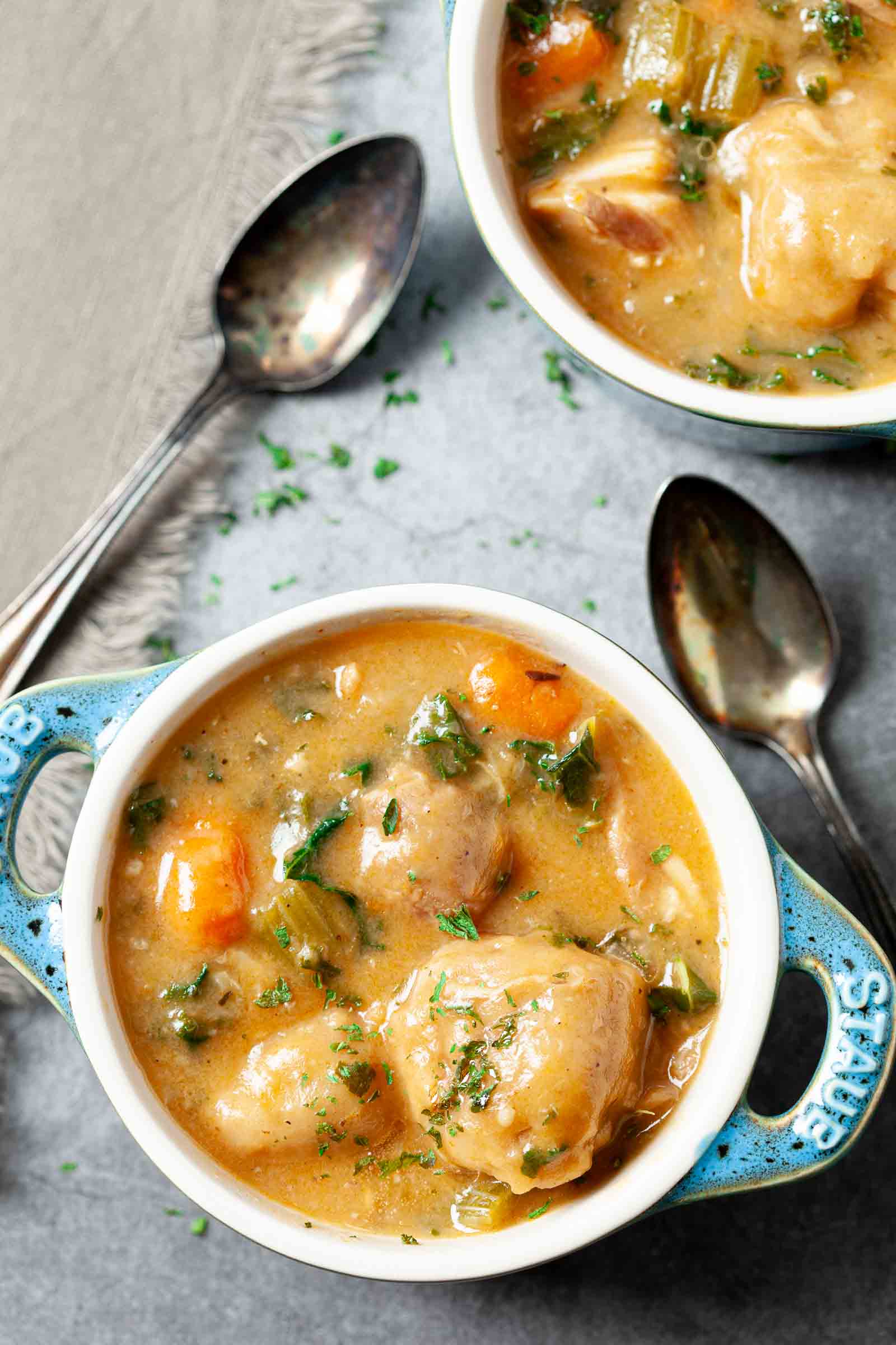 White bowl full of Instant Pot Chicken and Dumplings with a spoon sitting on the counter.