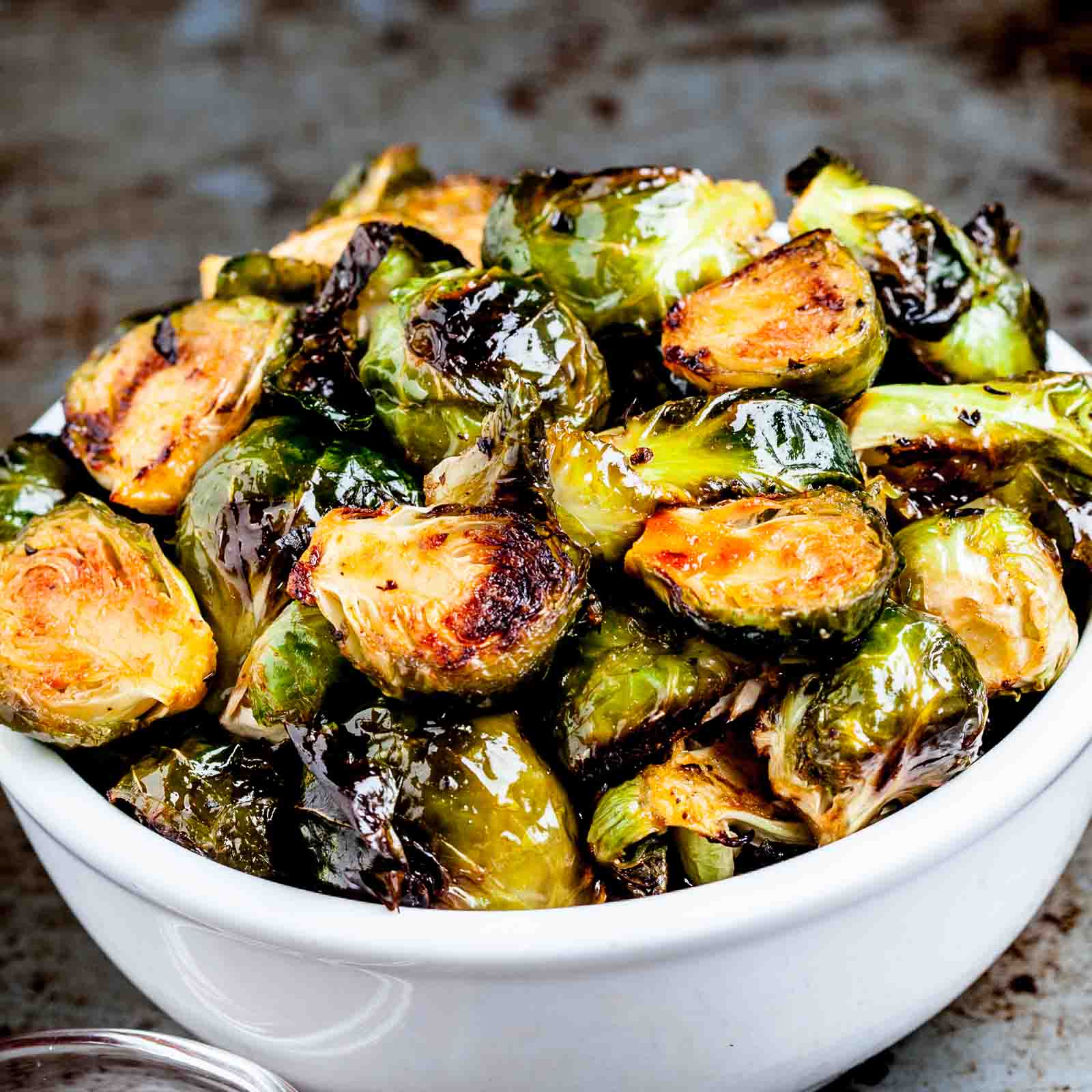 Close up of oven roasted Brussels sprouts in a white serving bowl.